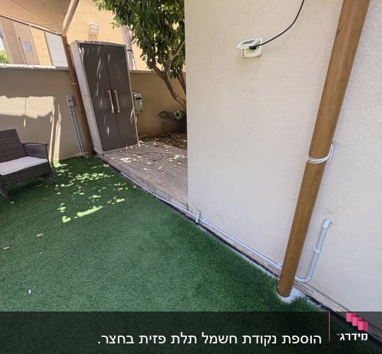 חצר עם דשא סינתטי ושקע חשמלי על הקיר